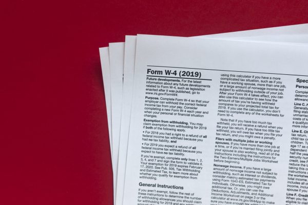 Photo of a stack of forms. On top is a W-4 exemption withholding form for the IRS.