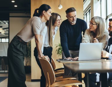 People in an office standing around a table discussing talent acquisition